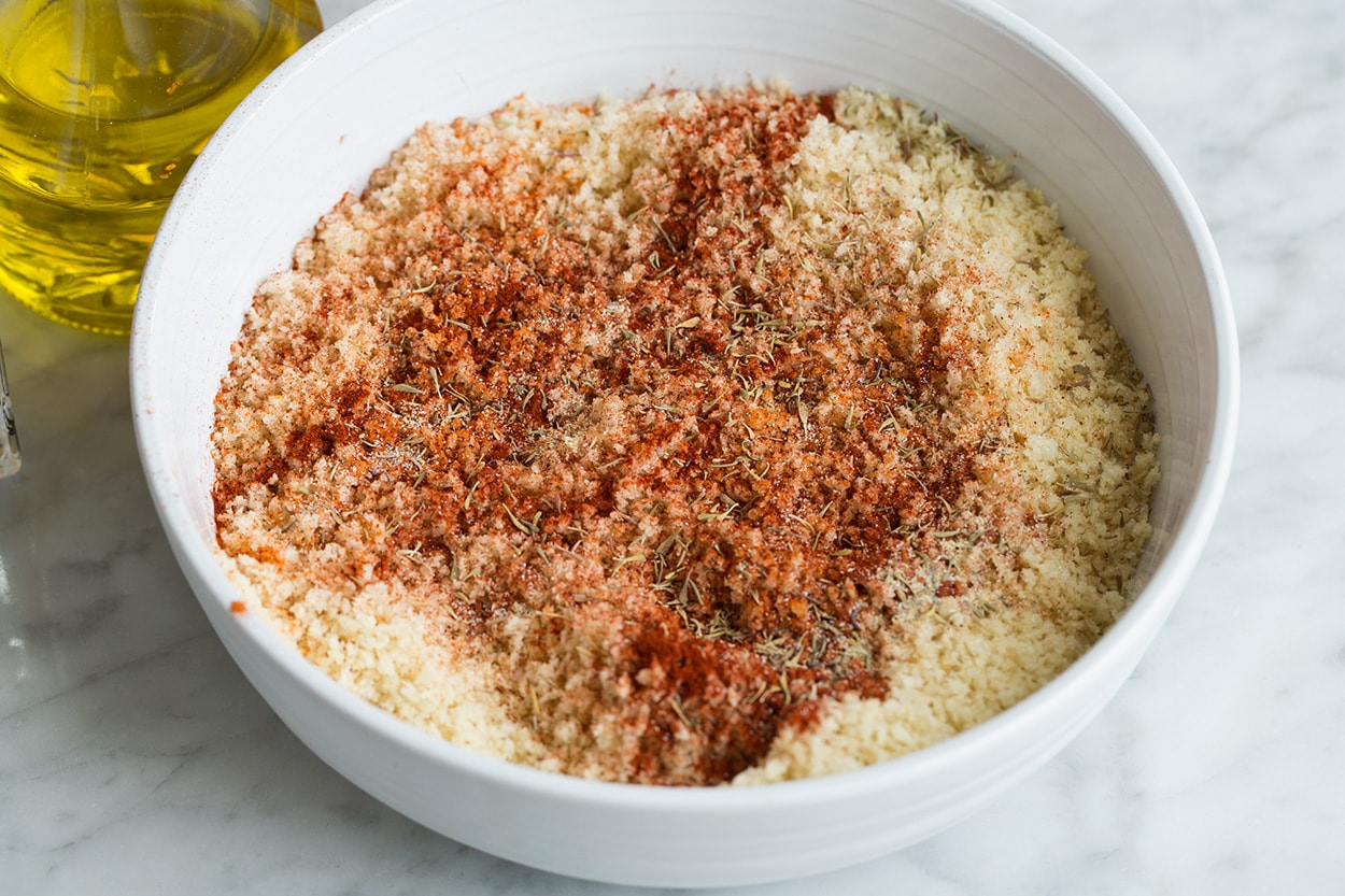 Mixing panko with olive oil and spices in a shallow dish for oven fried chicken.