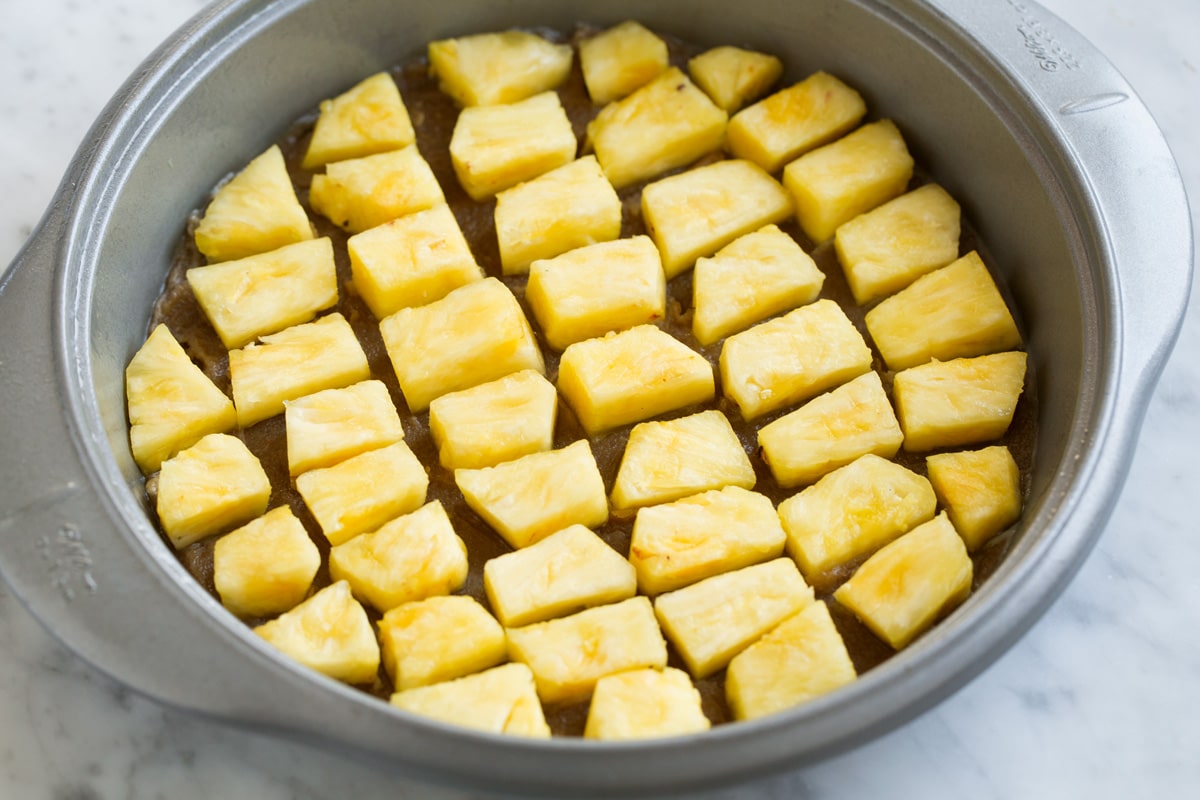 Adding fresh pineapple chunks over brown sugar layer in cake pan.