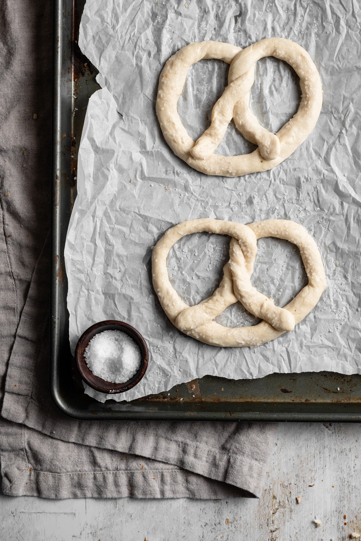 Homemade Soft Pretzels Image showing how to make soft pretzels. Shaping dough into pretzel shapes and they're placed on a parchment paper lined baking sheet to bake.