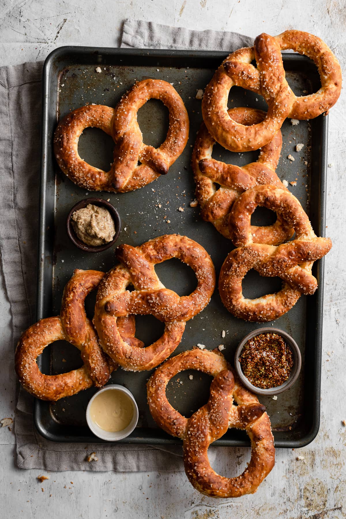 Homemade Soft Pretzels Overhead image of seven soft pretzels on a dark baking sheet.