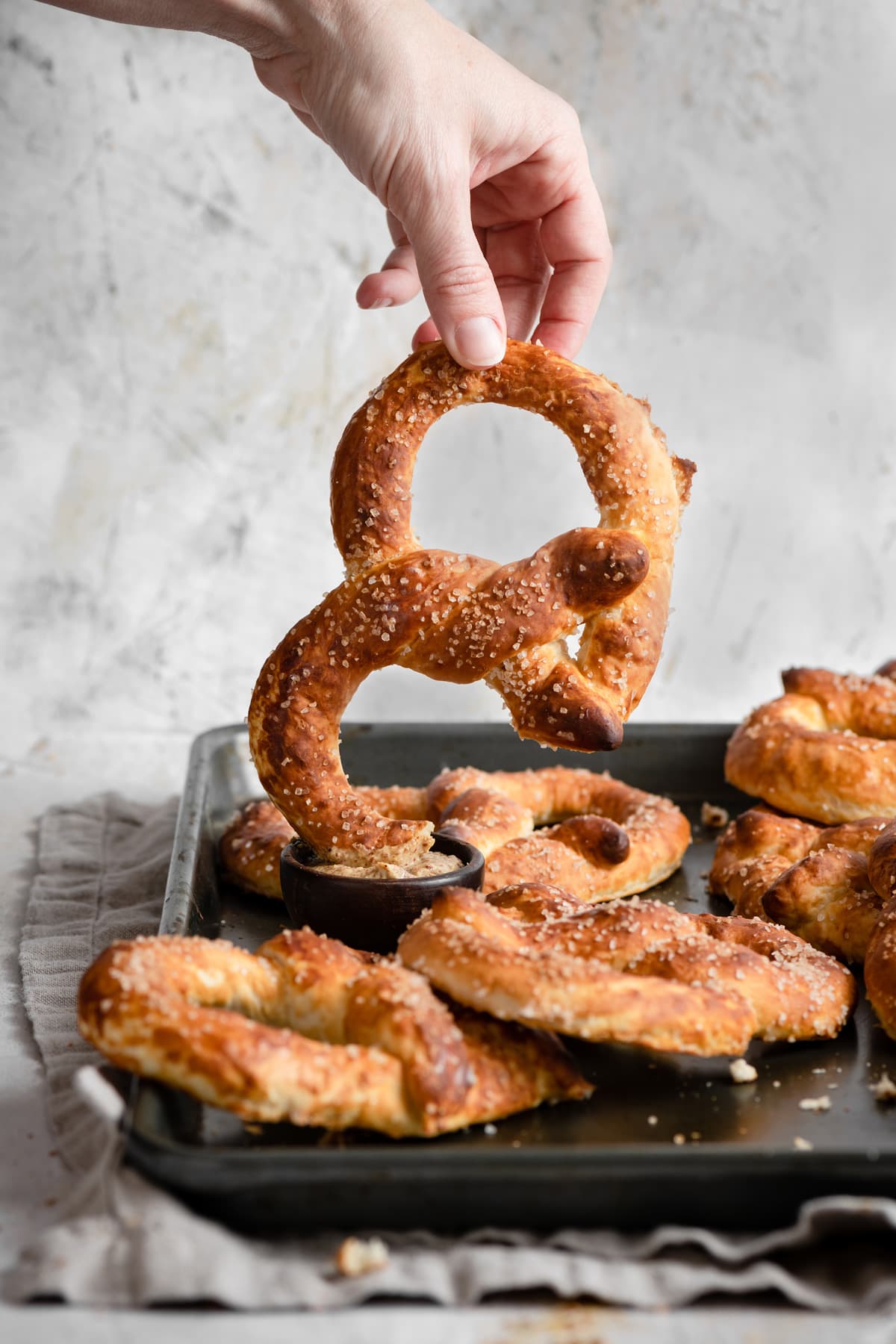 Homemade Soft Pretzels Recipe Dipping pretzel into mustard dipping sauce.