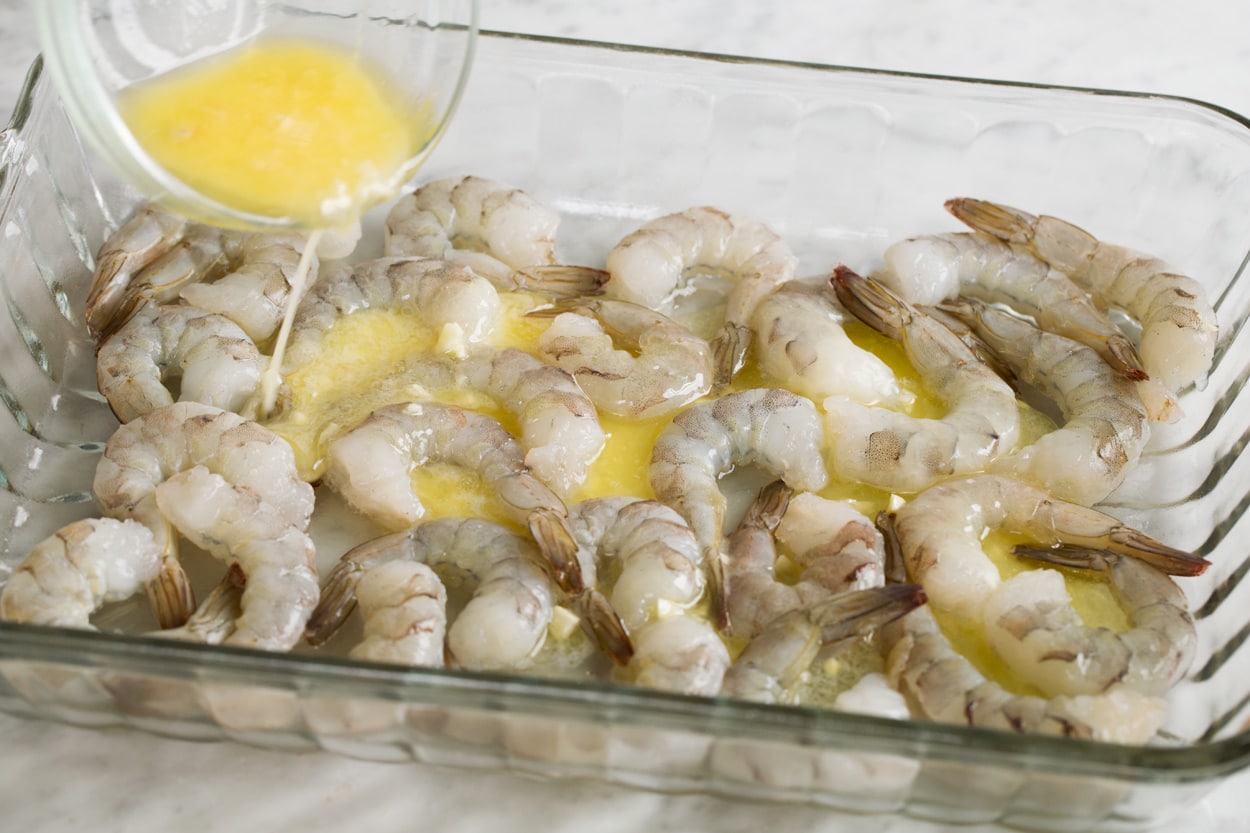 Baked Shrimp with Garlic Lemon Butter Sauce Showing how to make baked shrimp. Pouring garlic lemon butter over shrimp in baking dish.