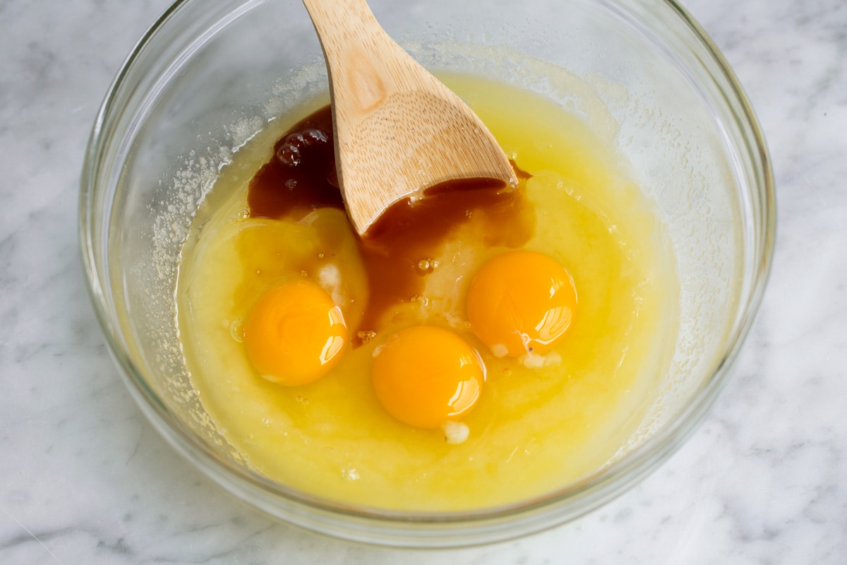 Adding eggs and vanilla to mixing bowl to make brownies.
