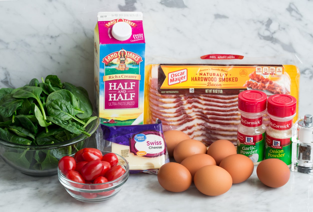 Frittata Recipe (Bacon, Spinach, Tomato and Swiss) Ingredients needed to make a frittata shown here including eggs, bacon, swiss cheese, spinach, tomatoes, half and half, garlic powder, onion powder, salt and pepper.