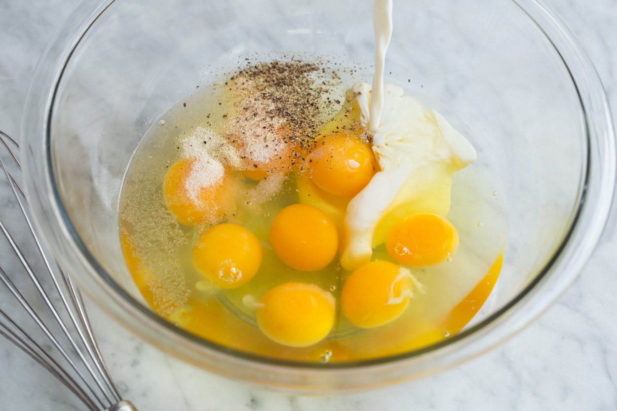 Frittata Recipe (Bacon, Spinach, Tomato and Swiss) Showing how to make a frittata, mixing eggs, spices and half and half in a glass mixing bowl.