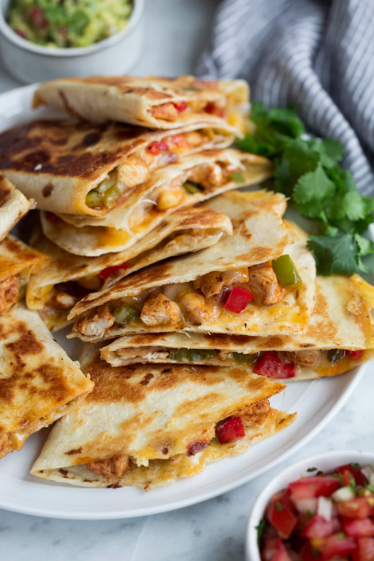 Quesadillas on a plate served with guacamole and salsa. 