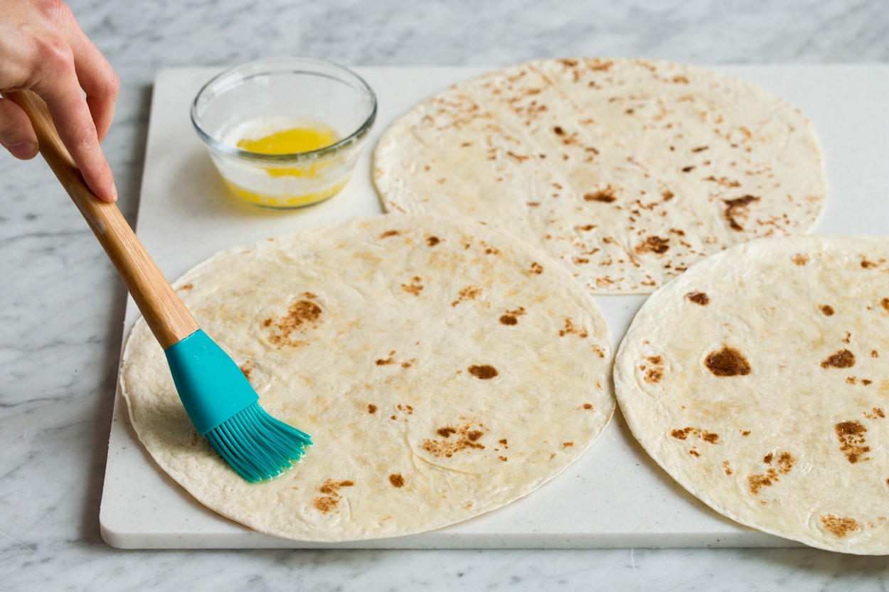 Brushing tortillas with melted butter to make quesadillas.