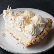 Single slice of coconut cream pie on a white dessert plate.