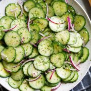 Cucumber Salad in white serving bowl set over a dark grey napkin.