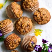 Overhead image of morning glory muffins on a marble surface decorated with spring flowers.