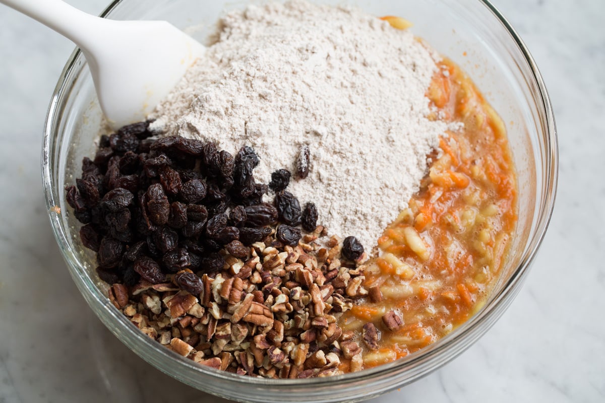 Adding flour mixture to wet mixture along with raisins and pecans. Folding with a rubber spatula to incorporate.