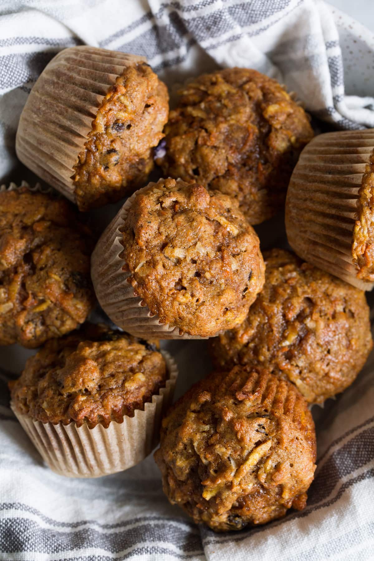 Morning glory muffins in a serving bowl with a kitchen towel.