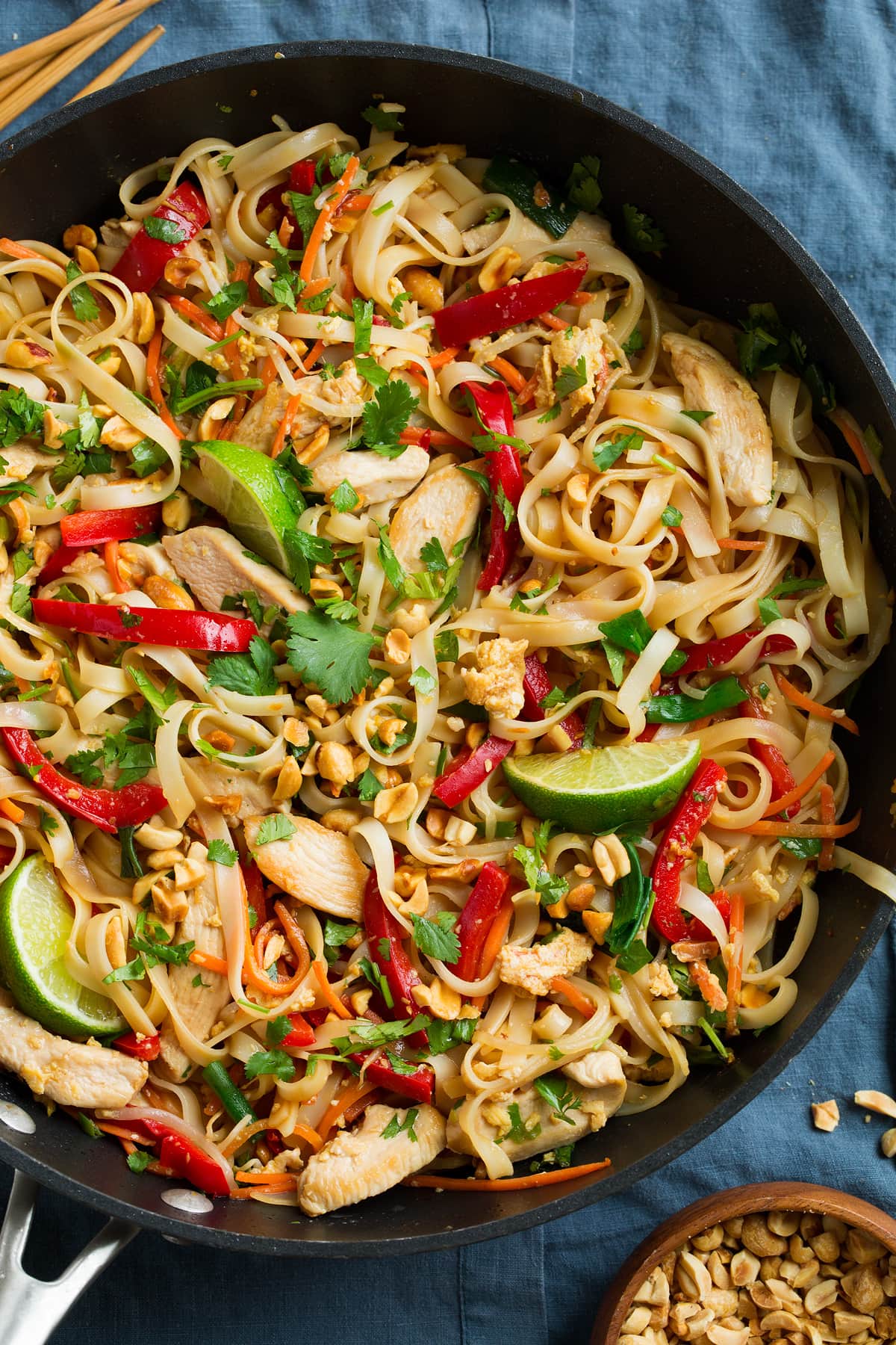 Pad Thai in a black wok with chicken and fresh vegetables.