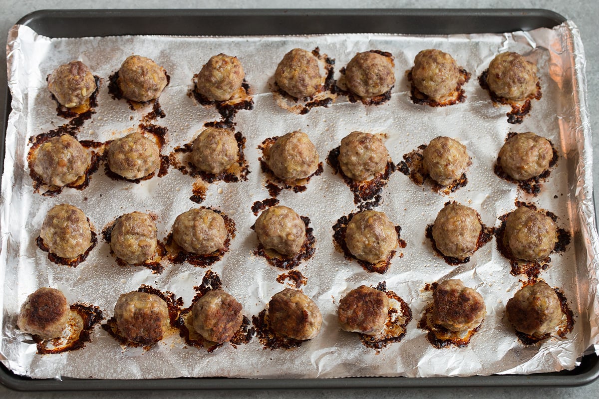 28 shaped Swedish meatballs on foil lined baking sheet, shown after baking.
