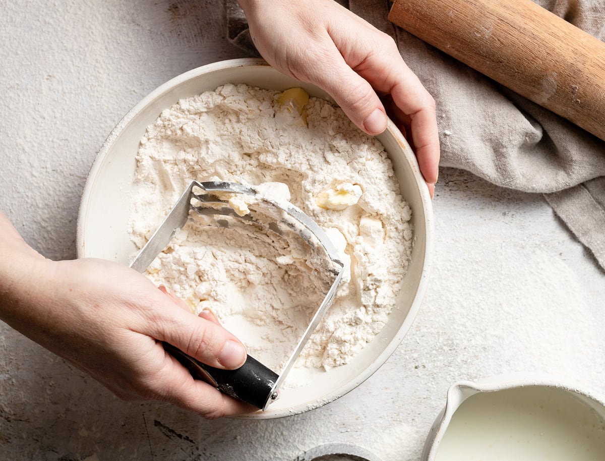 Showing how to make biscuits, cutting butter into flour mixture using a pastry cutter.