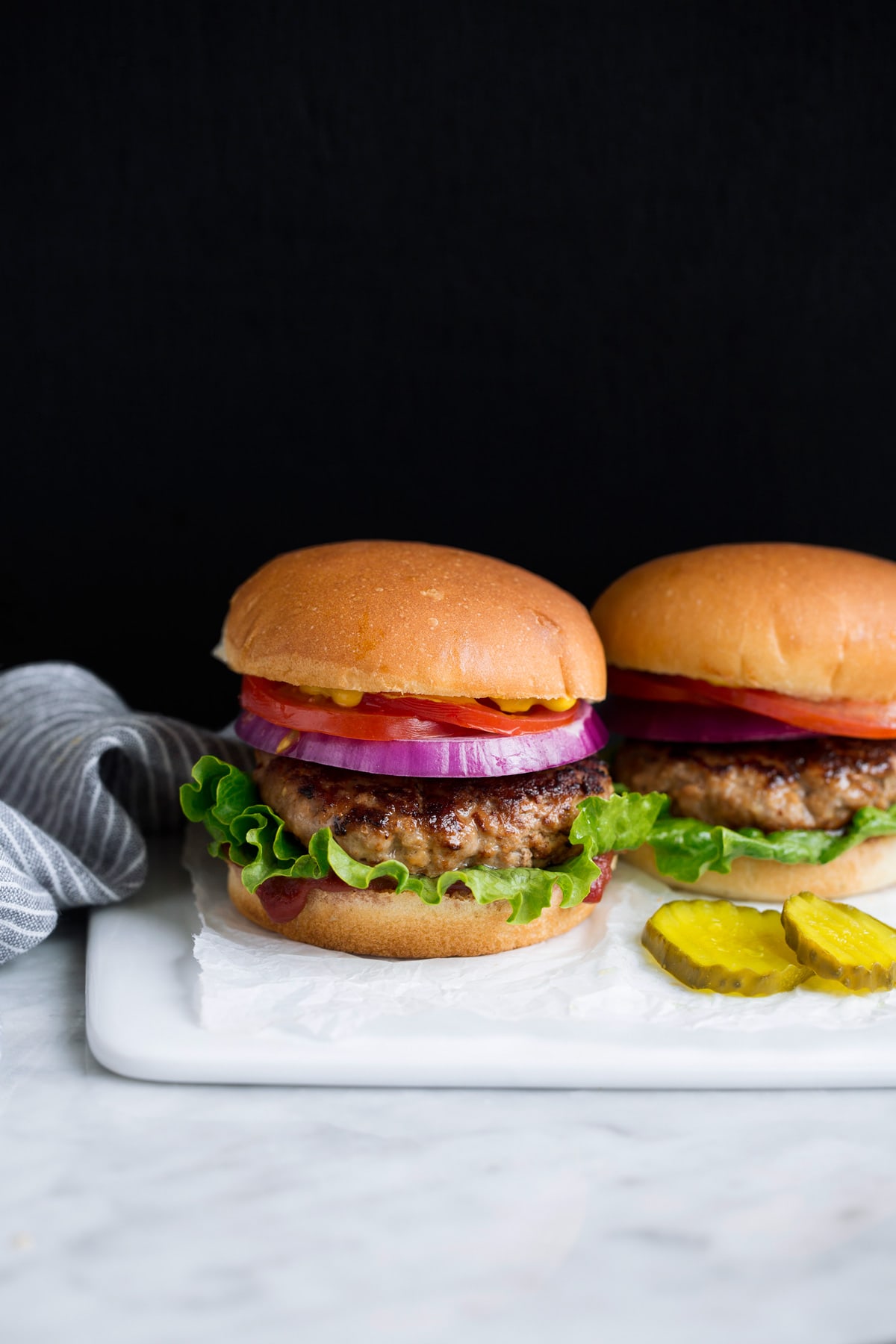 Two turkey burgers on a white serving platter.
