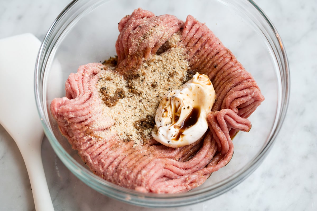 Showing how to make turkey burgers, mixing turkey burger patty mixture in a glass mixing bowl.