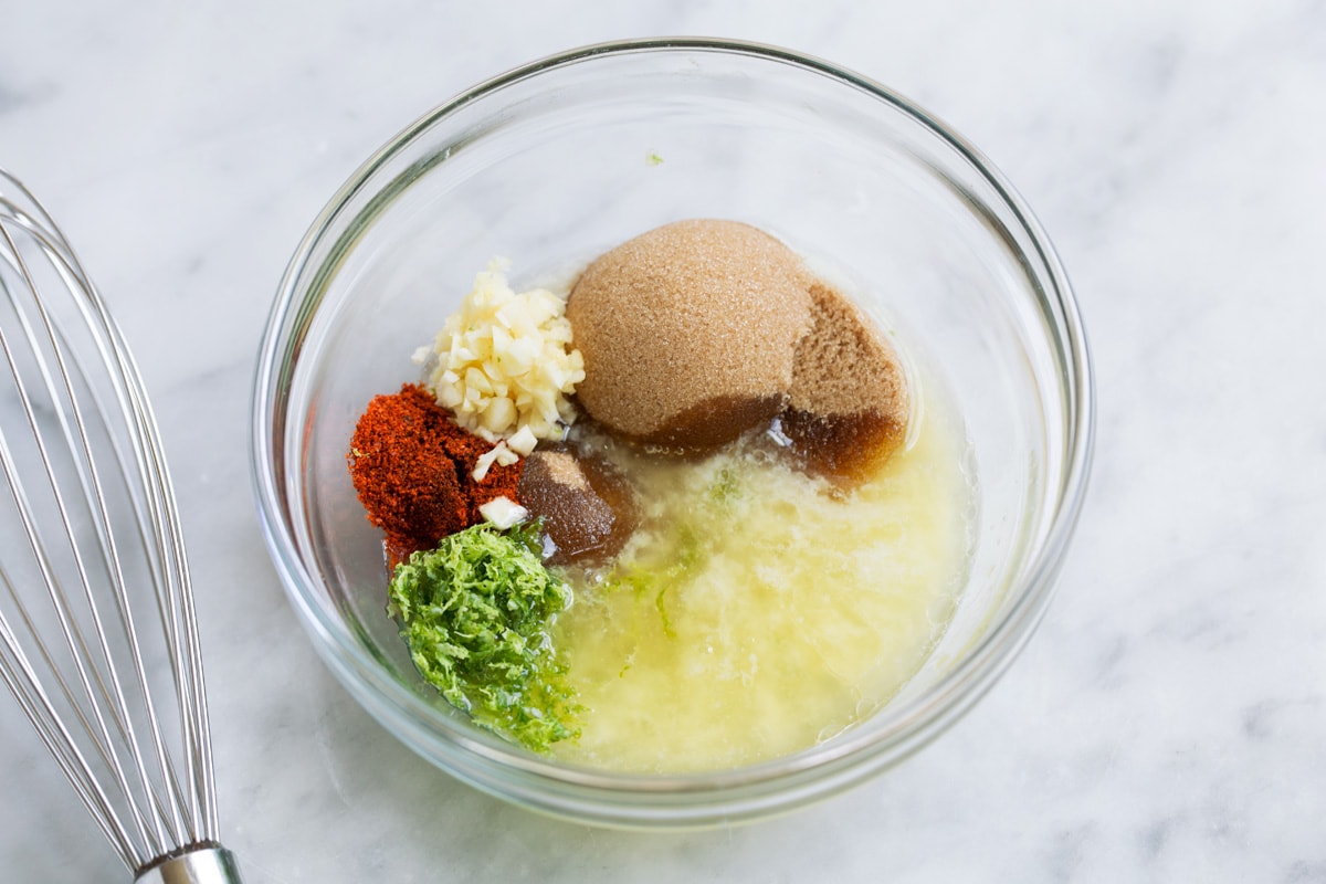 Showing how to make sauce for baked salmon. Mixing melted butter, brown sugar, lime, garlic, cayenne pepper in a small mixing bowl.
