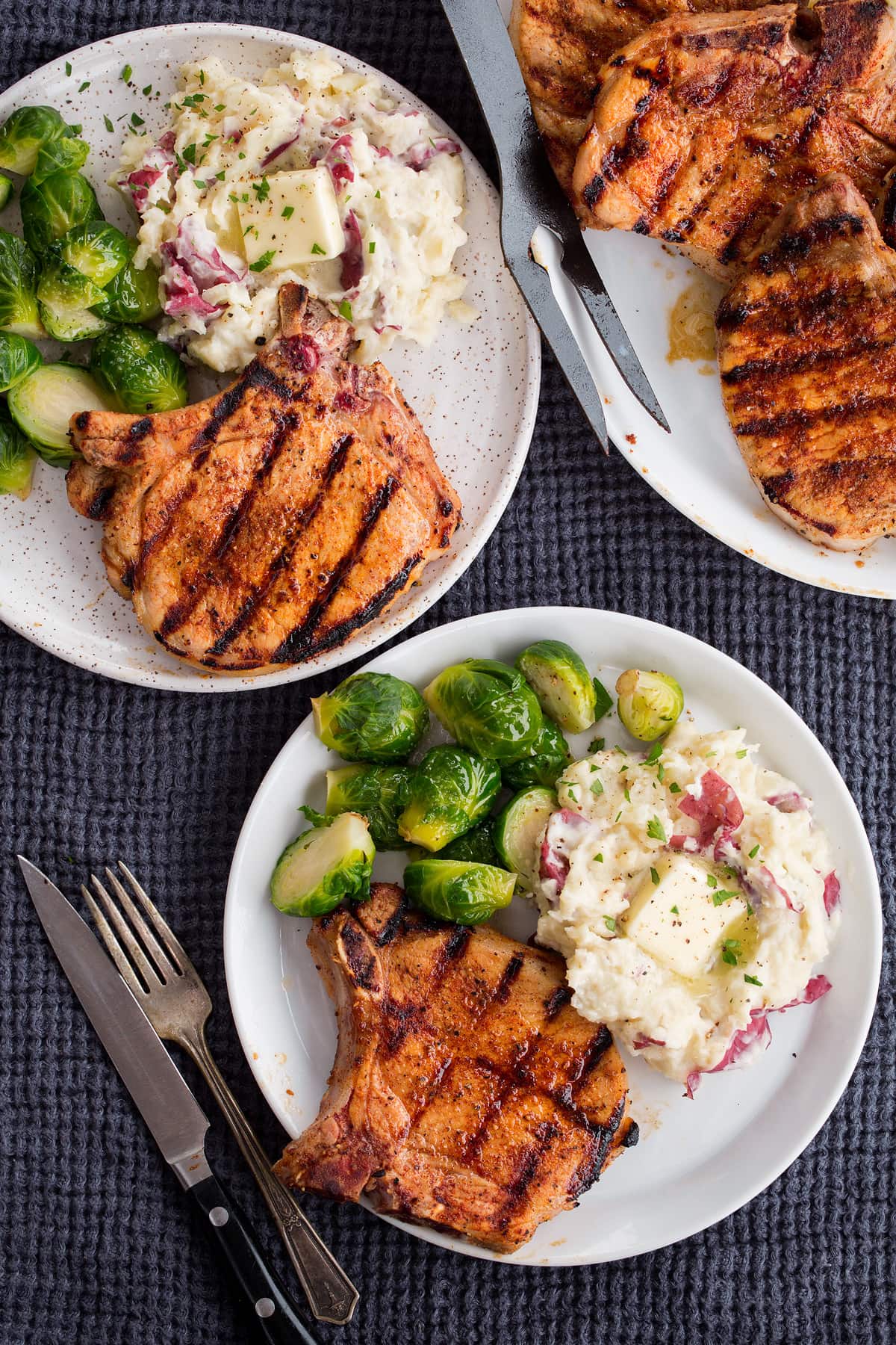 Grilled Pork Chops Showing serving suggestions sides to pair with grilled pork chops. Plate with pork chops, mashed potatoes and Brussesls sprouts.