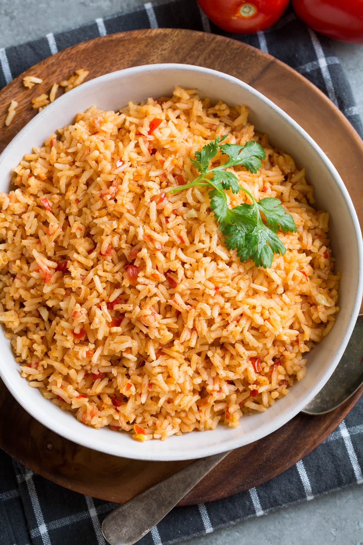 Mexican rice in a white serving bowl set over a wooden plate.