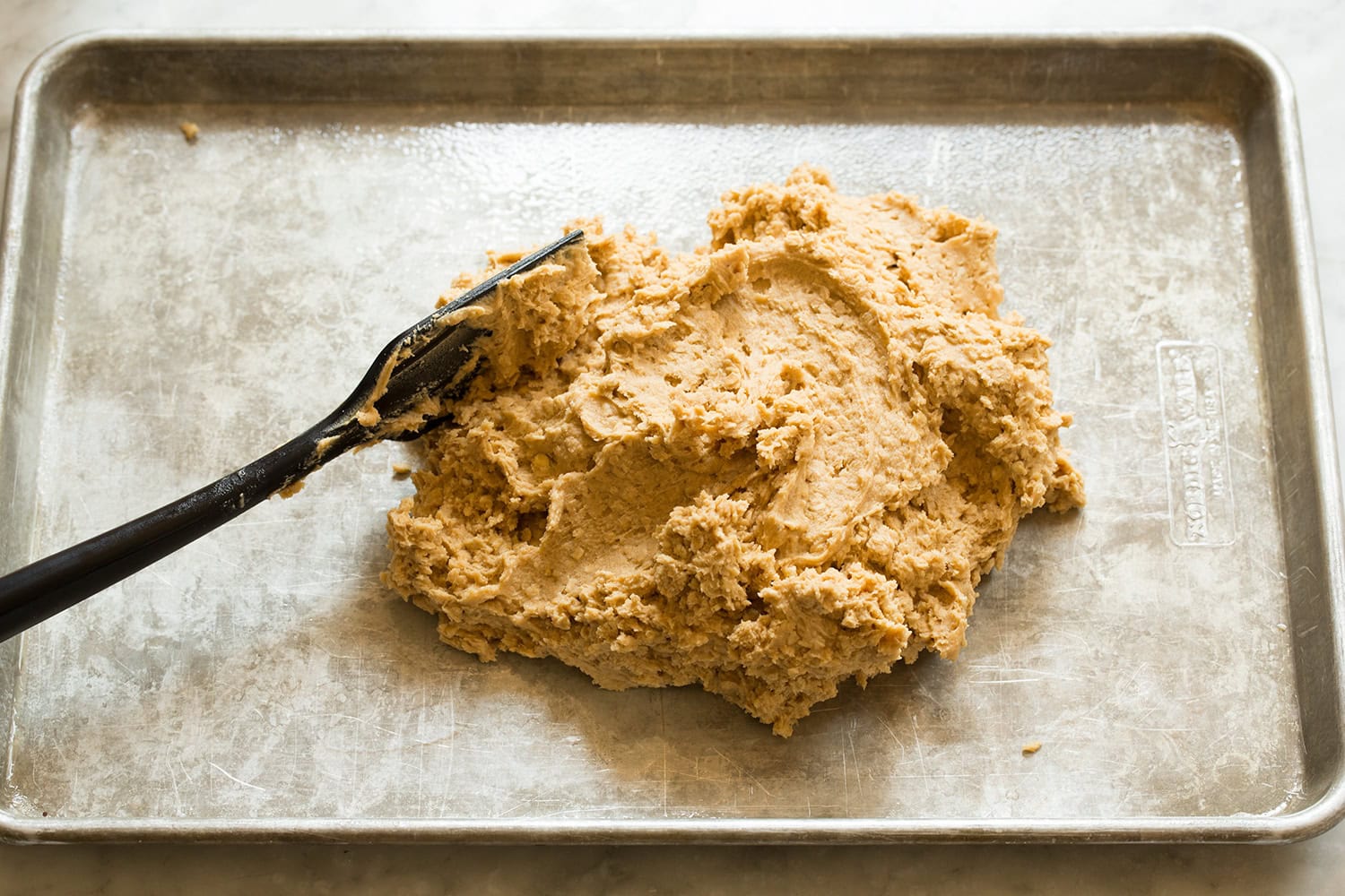 Completed oat peanut butter cookie dough dumped into a mound on baking sheet.