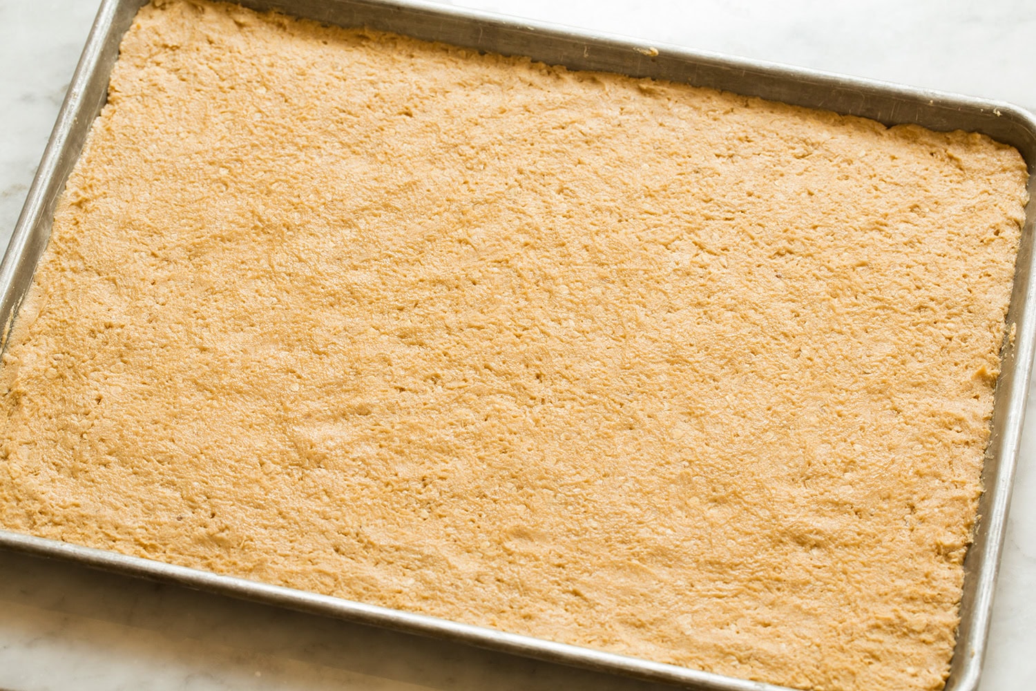 Peanut butter cookie dough spread onto baking sheet evenly.
