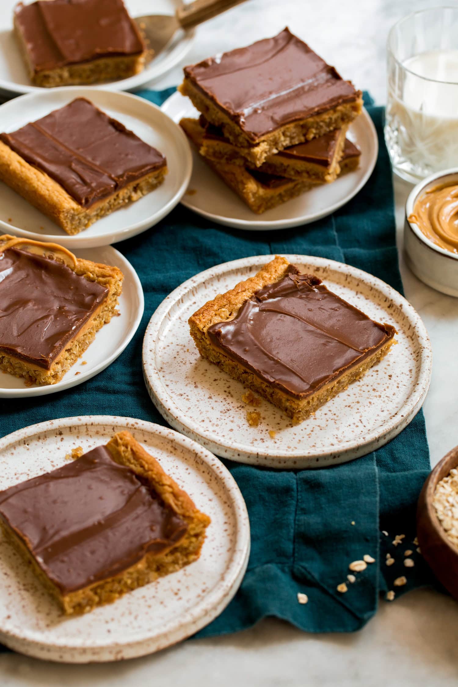 Single servings of peanut butter bar cookie squares on small dessert plates.