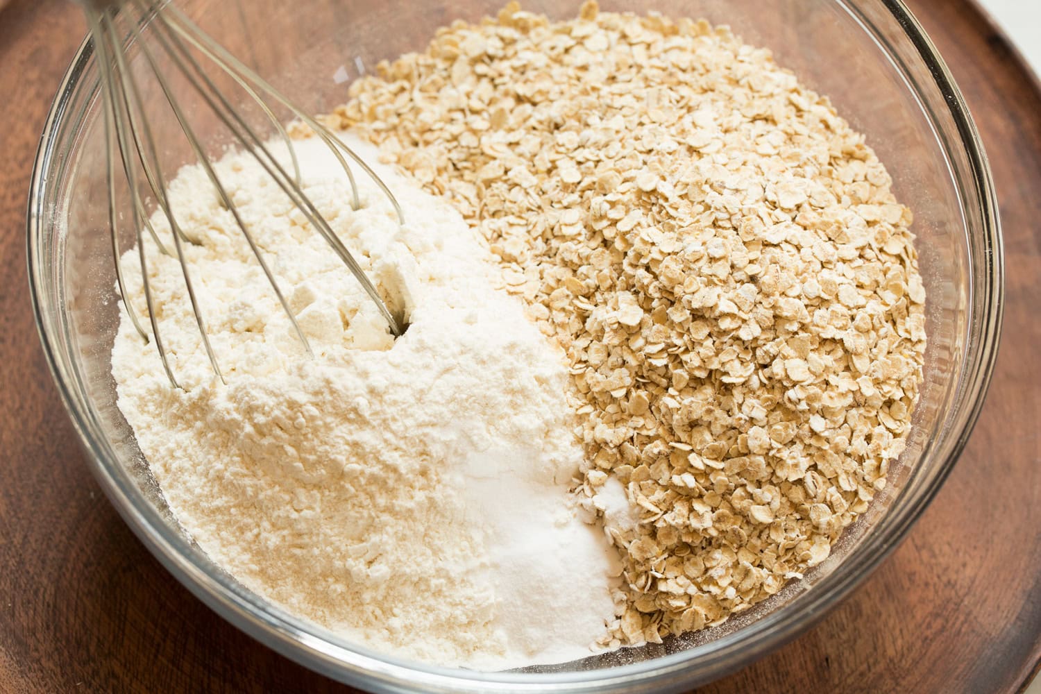 Mixing oats and flour in a glass bowl for cookie bars.