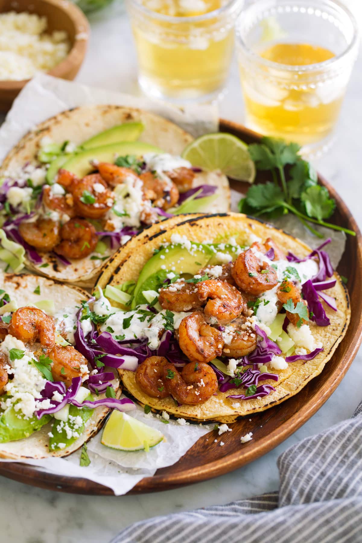 Three shrimp tacos on a wooden platter.