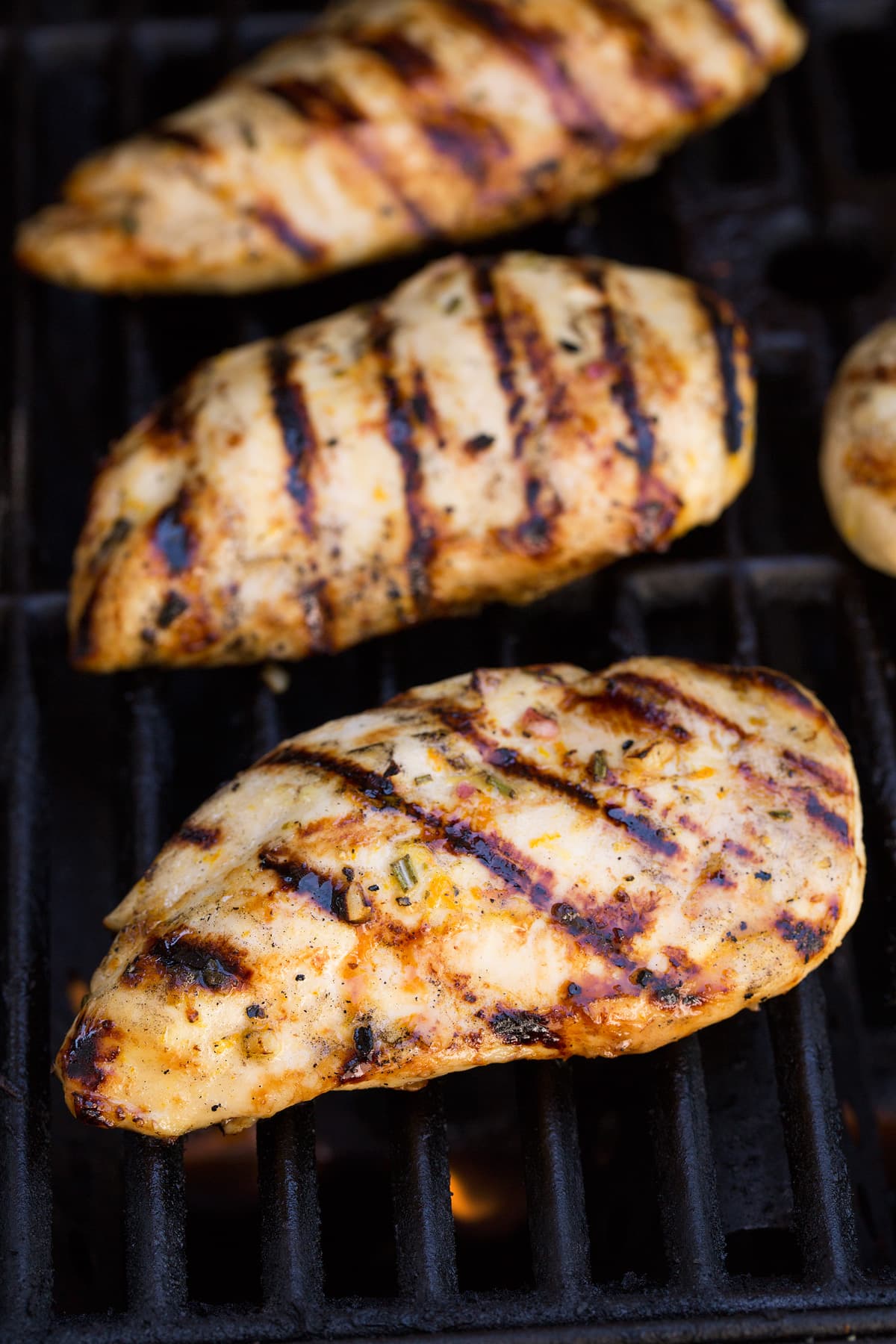 Three chicken breasts on a grill.