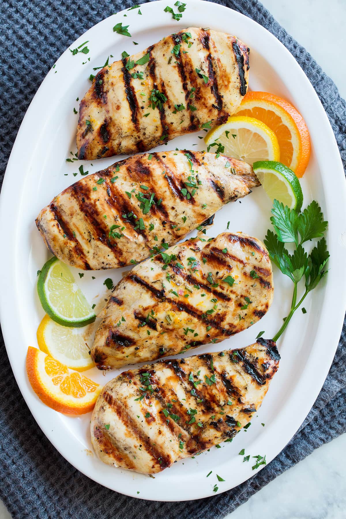 Overhead image of chicken breasts coated with marinade on a serving platter.