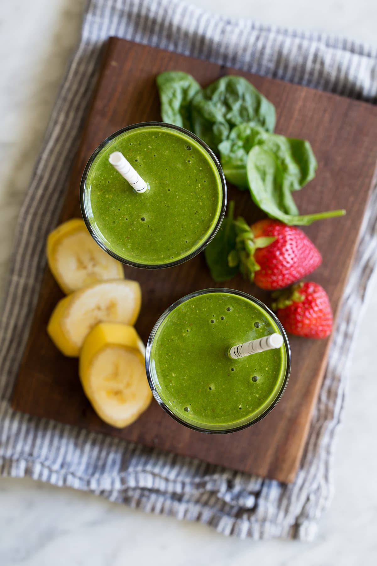 My go-to Green Smoothie! Healthy and perfectly filling. Made with spinach, berries, bananas, oats and almonds. #smoothie #greensmoothie #healthy #breakfast #smoothie Overhead image of two glasses of green smoothies.