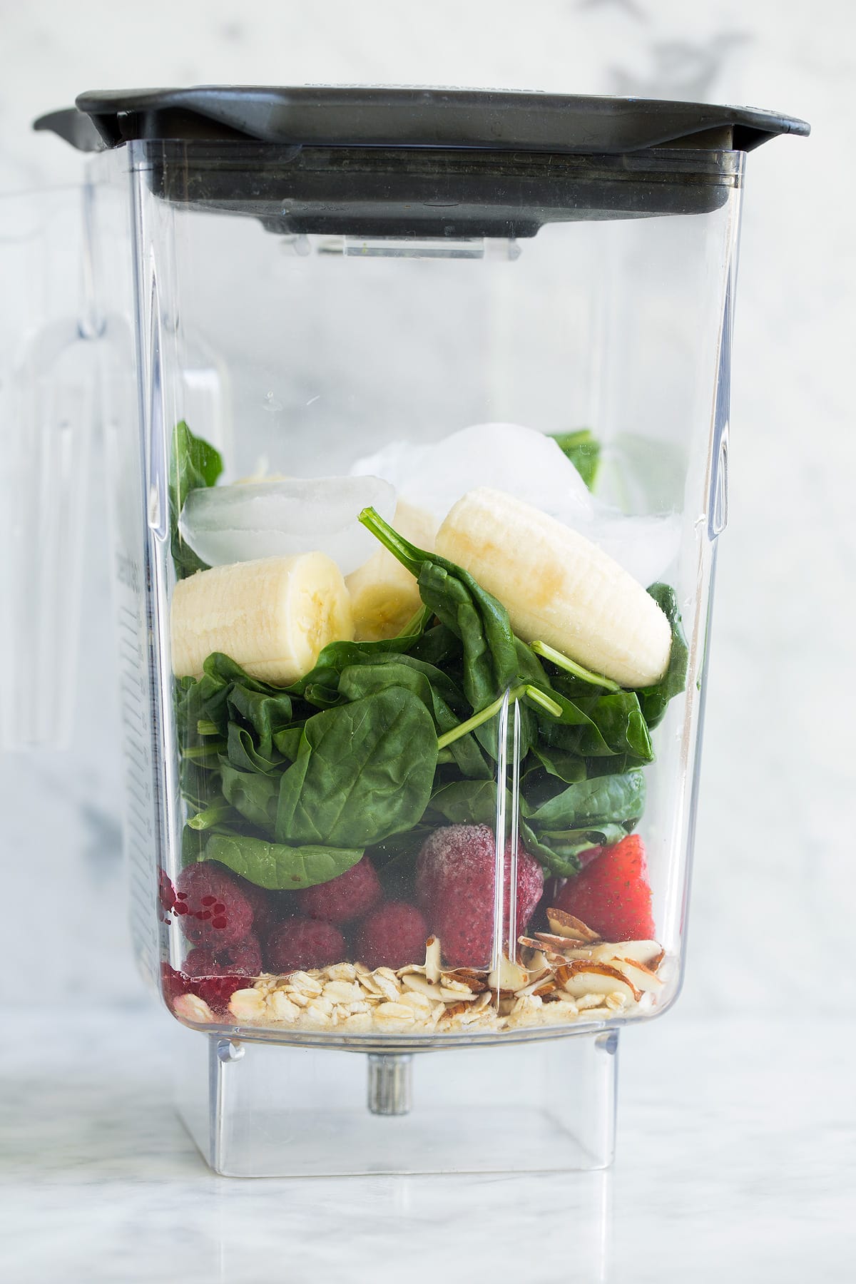 My go-to Green Smoothie! Healthy and perfectly filling. Made with spinach, berries, bananas, oats and almonds. #smoothie #greensmoothie #healthy #breakfast #smoothie Green smoothie ingredients in a blender jar before blending.