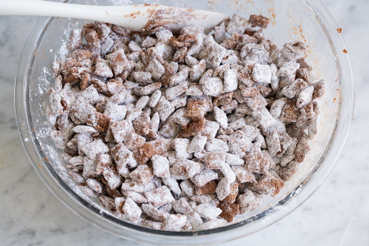 Perfect Puppy Chow {Muddy Buddies}! - one of my go-to treats! These are dangerously addictive! Perfect for parties, holidays and traveling too. #muddybuddies #puppychow #treat #chocolate #chex #peanutbutter Finished bowl of muddy buddies in mixing bowl.