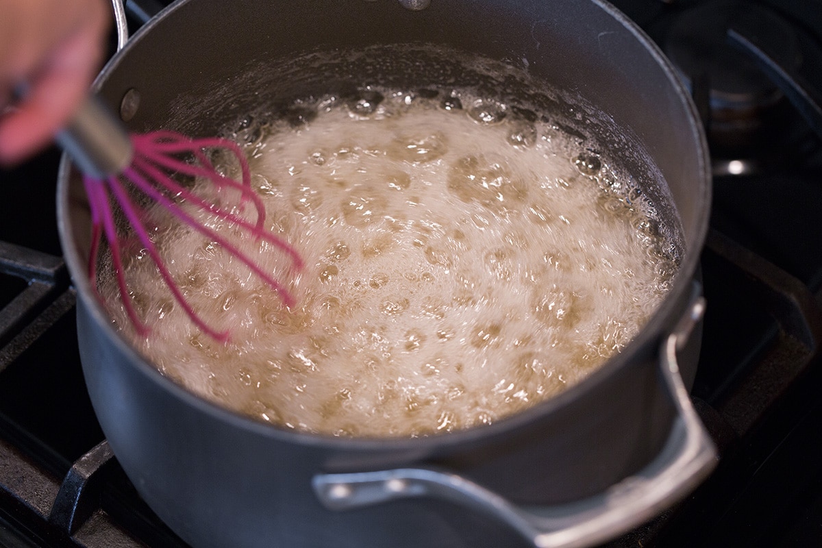 Sugar, pectin and water mixture boiling in a pot.