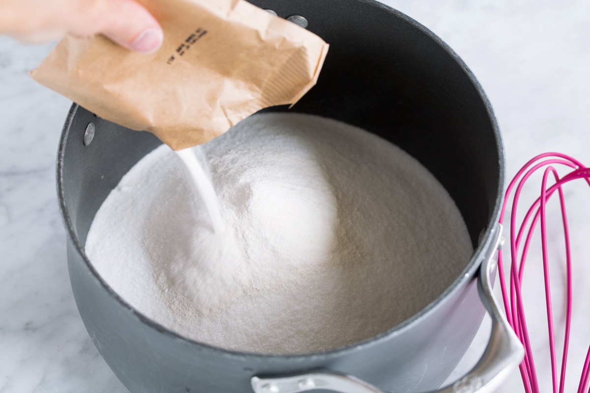 Adding pectin to sugar in pot.