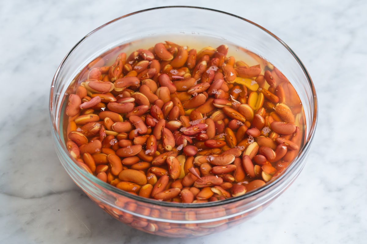Red beans soaking in a glass bowl with water.