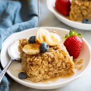 Slice of baked oatmeal topped with fresh fruit and maple syrup.