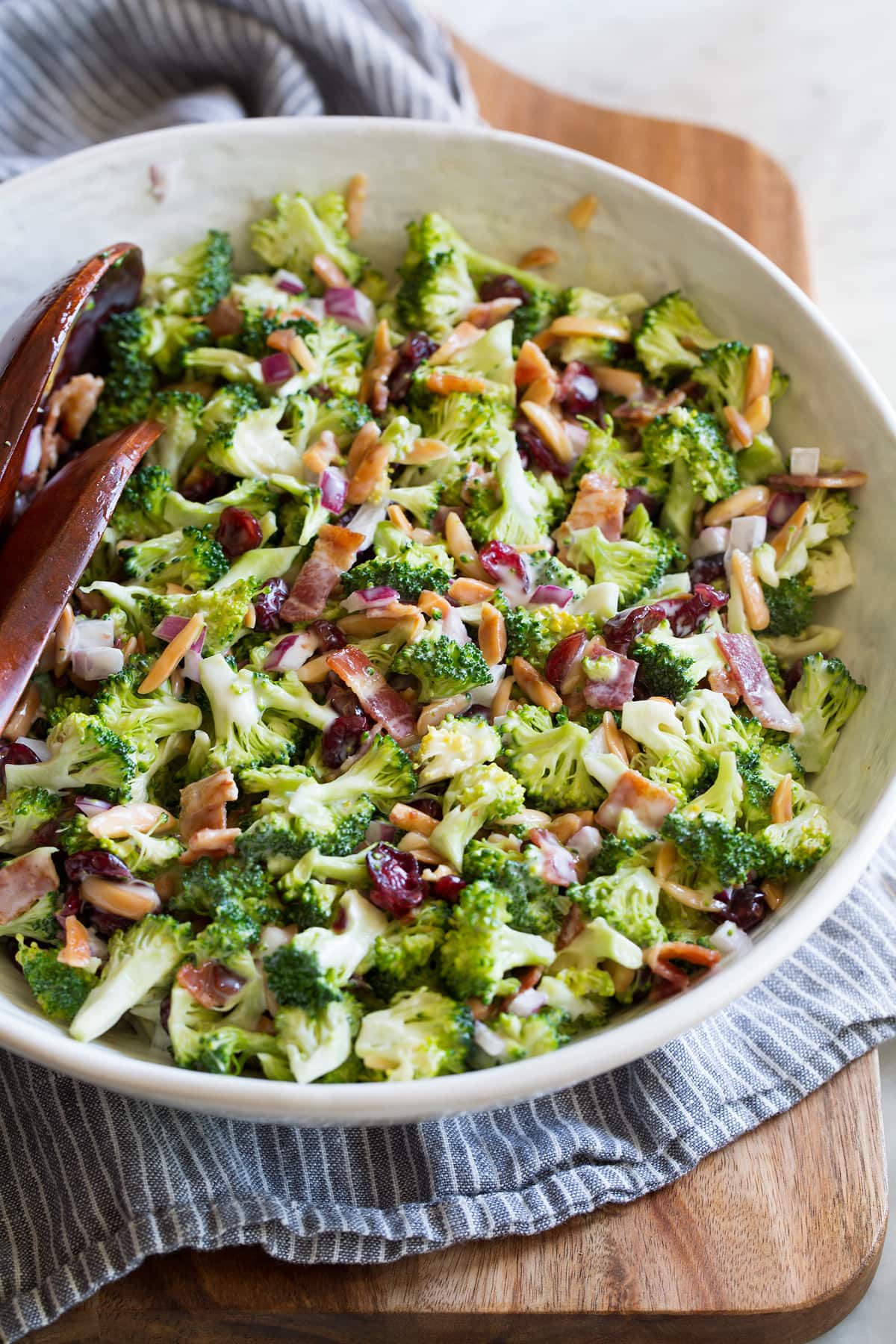 Classic broccoli salad in a salad bowl set over a wooden bread board.