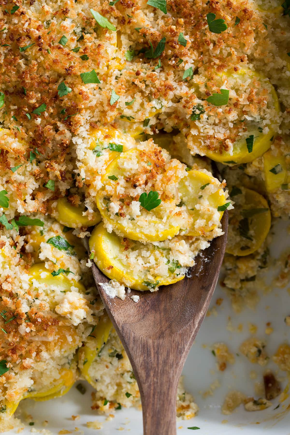 Close up image of wooden spoon with scoop of squash casserole.