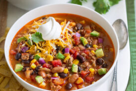 Two servings of taco soup in white bowls over a white platter.