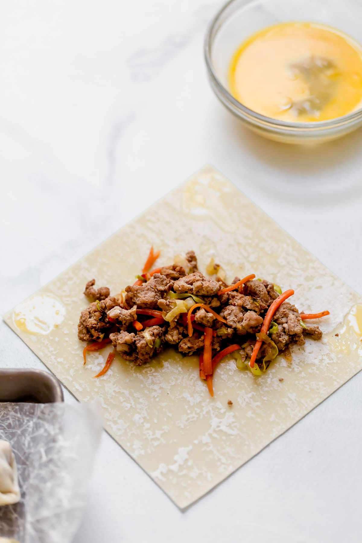 Egg Rolls Showing how to assemble egg rolls, placing egg roll filling in a row in center of egg roll wrapper.