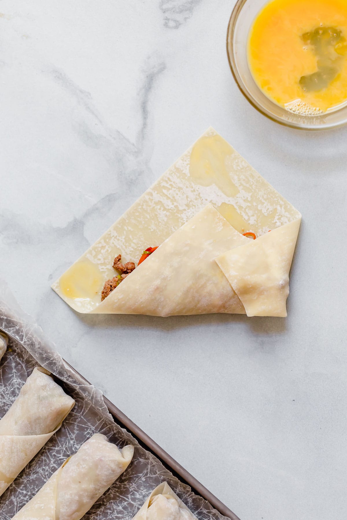 Egg Rolls Wrapping egg roll wrapper around filling with egg on edges to seal.