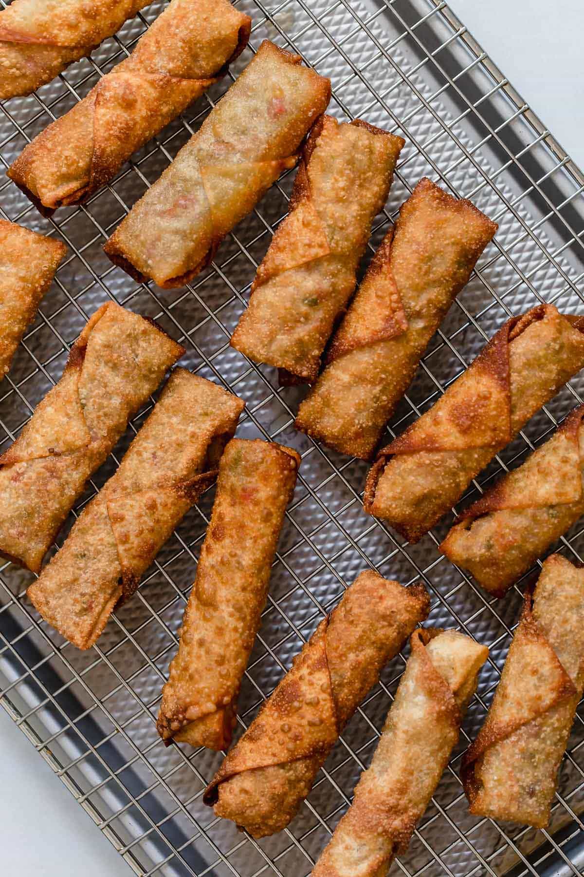 Egg Rolls {Fried or Baked} Egg rolls on a cooling rack set over a baking sheet.
