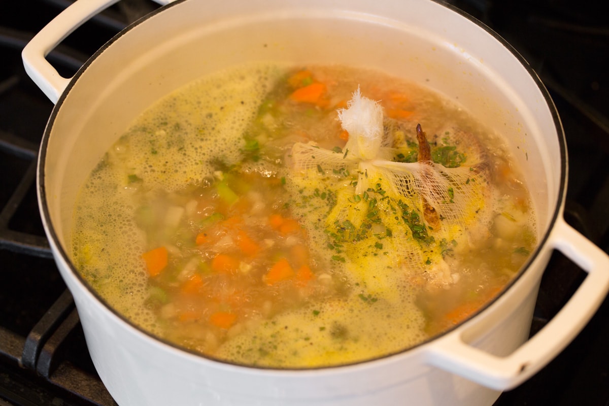 Simmering chicken noodle soup on stove top.