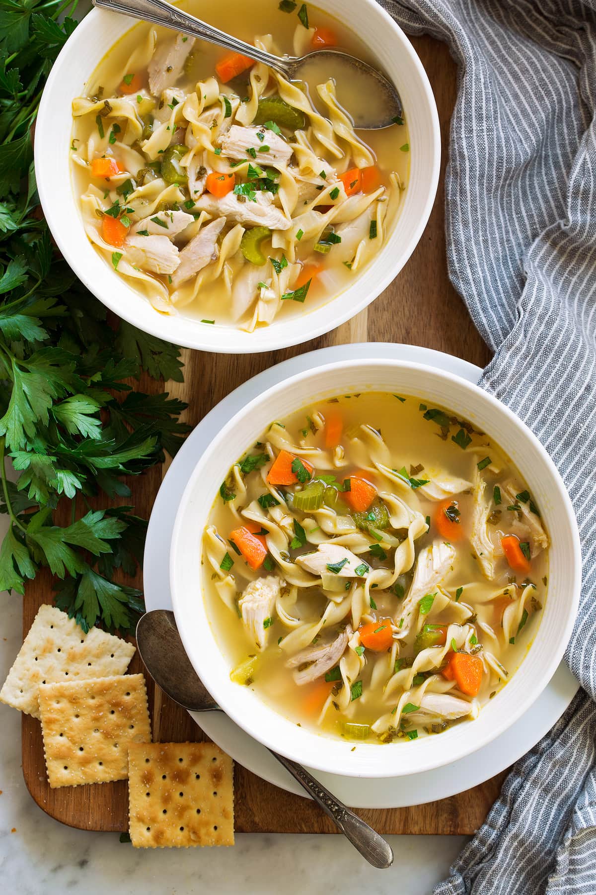 Two servings of the best chicken noodle soup in white bowls.