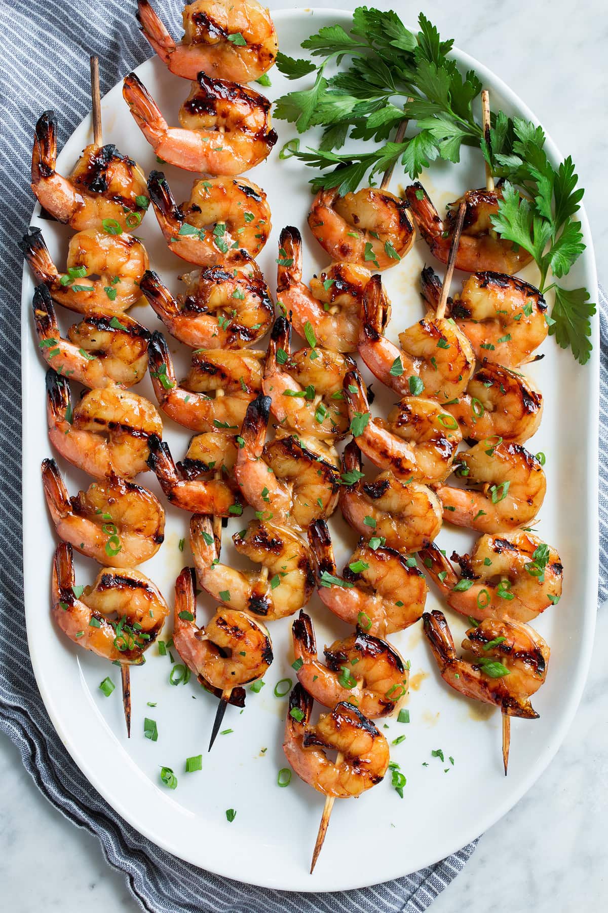 Five wooden skewers with grilled shrimp.