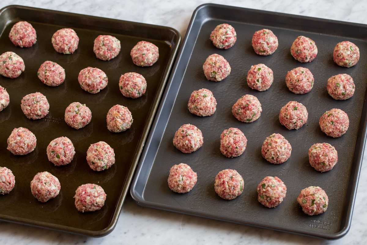Raw meatballs on two baking sheets.