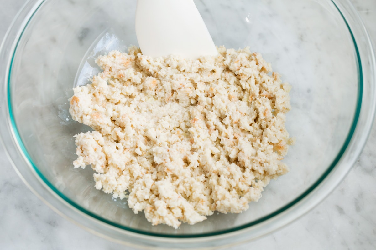 Mixing bread and milk mixture in a glass bowl.