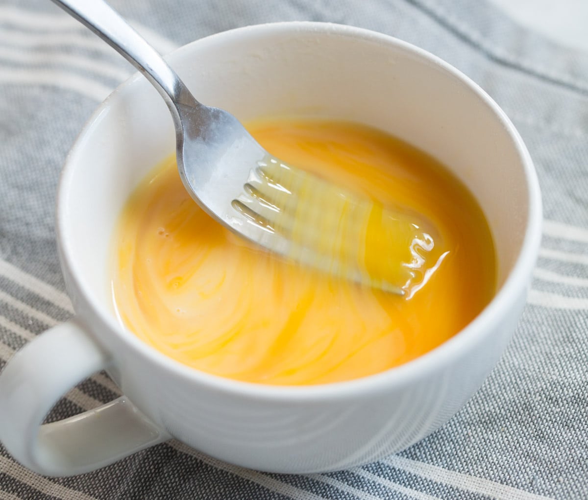 Mixing eggs and milk in mug with a fork